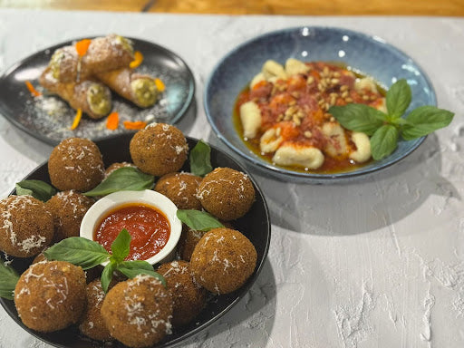 Italian dishes featuring arancini, gnocchi in tomato sauce, and cannoli, garnished with basil and cheese