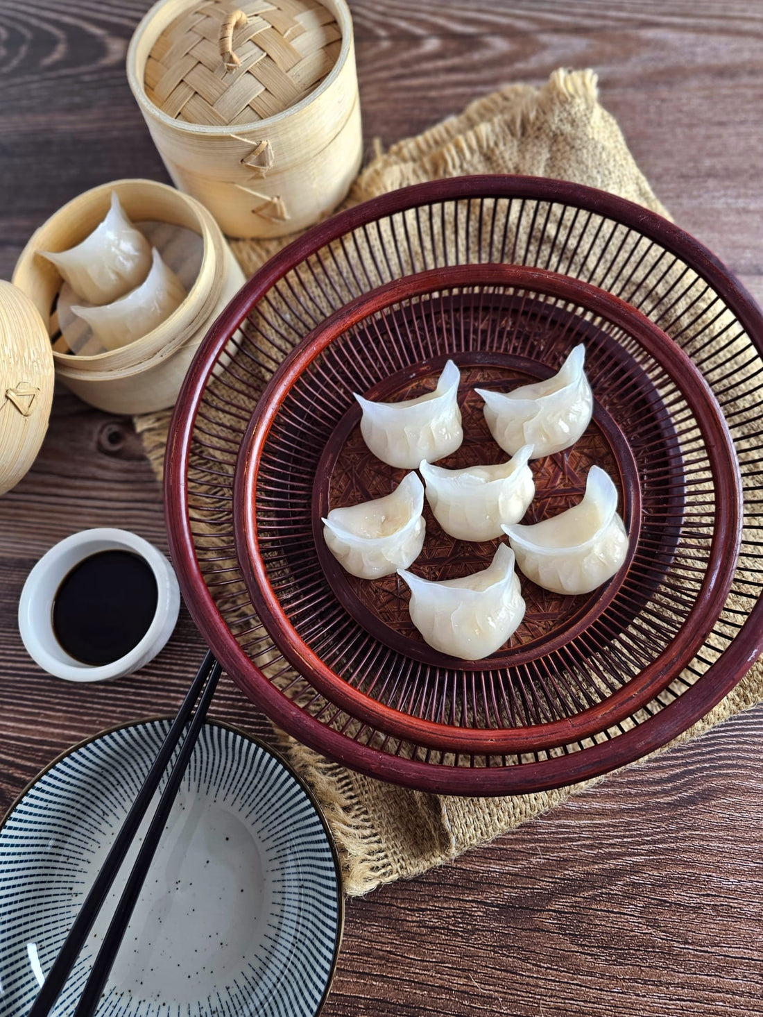 Handmade authentic dumplings neatly arranged on a bamboo tray, served with soy sauce and chopsticks.